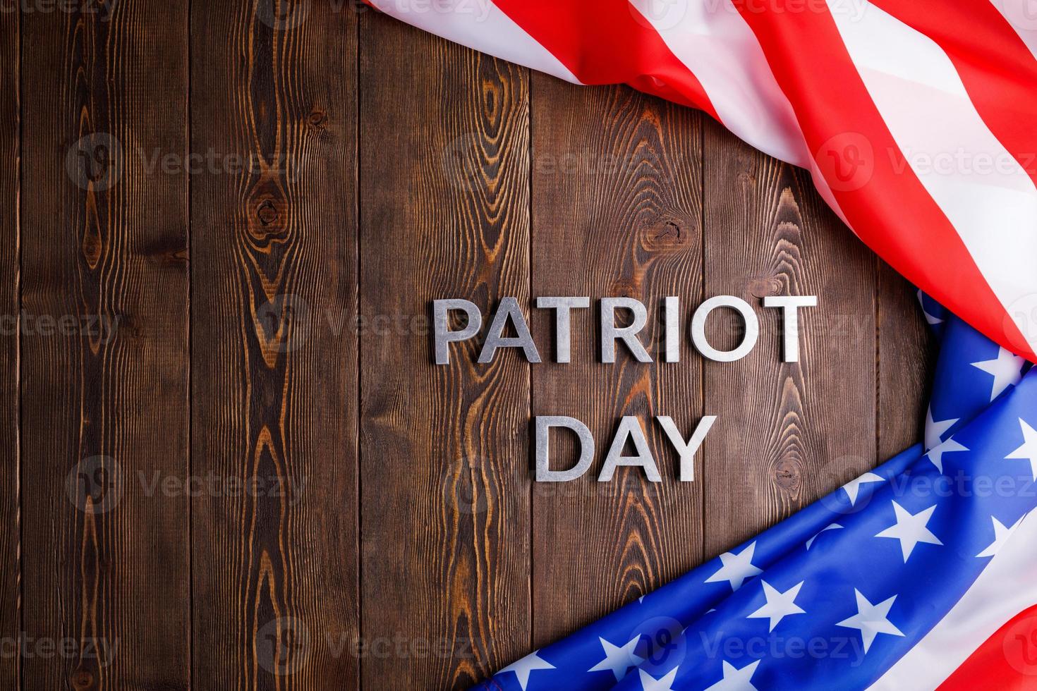 the words patriot day laid with silver metal letters on wooden board surface with crumpled usa flag photo