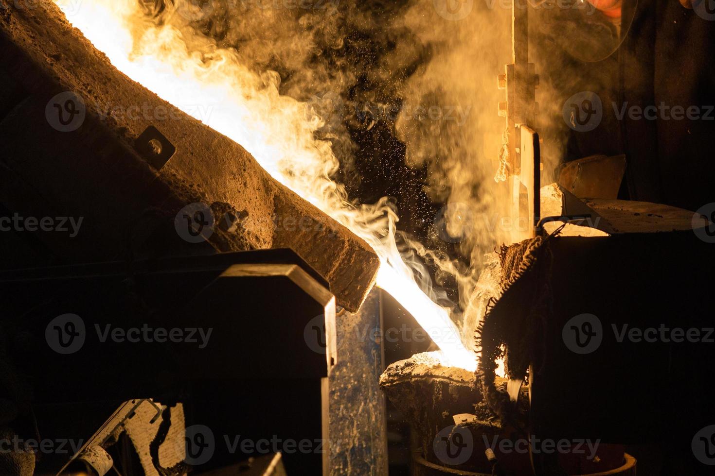 a process of ladle filling with molten hot steel from furnace with smoke - close-up with selective focus photo