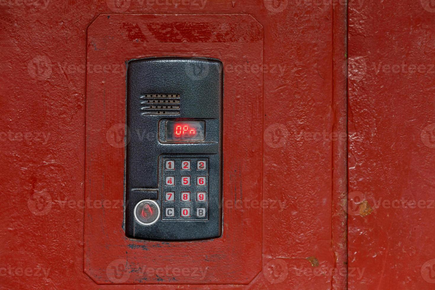 An intercom on old painted red steel surface with a keypad, digital display and rfid sensor for calling close-up photo