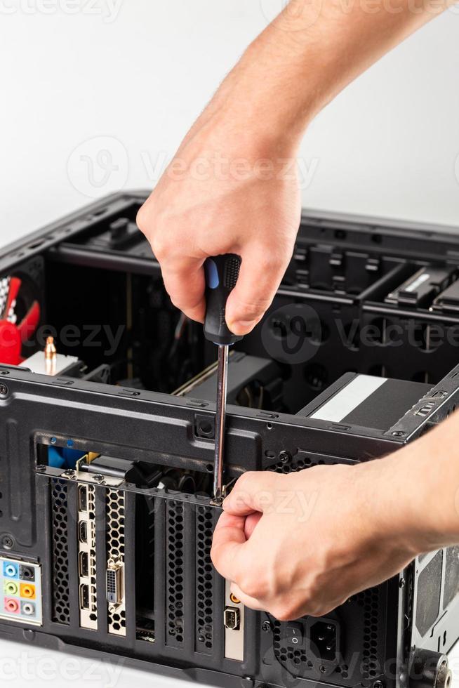 hands unscrewing a video card bracket while maintenance personal computer photo