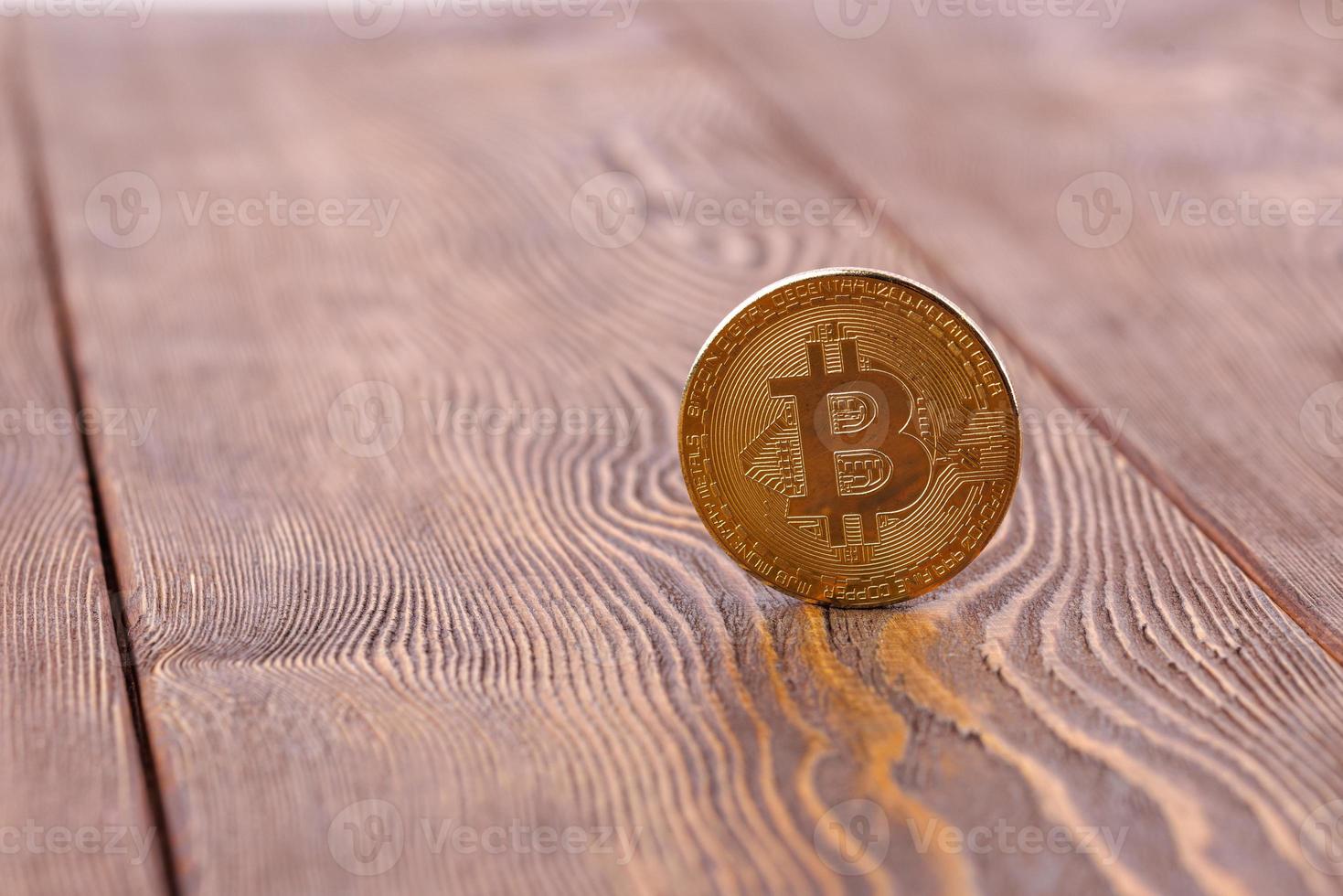 moneda bitcoin de pie sobre fondo de madera - primer plano con enfoque selectivo foto