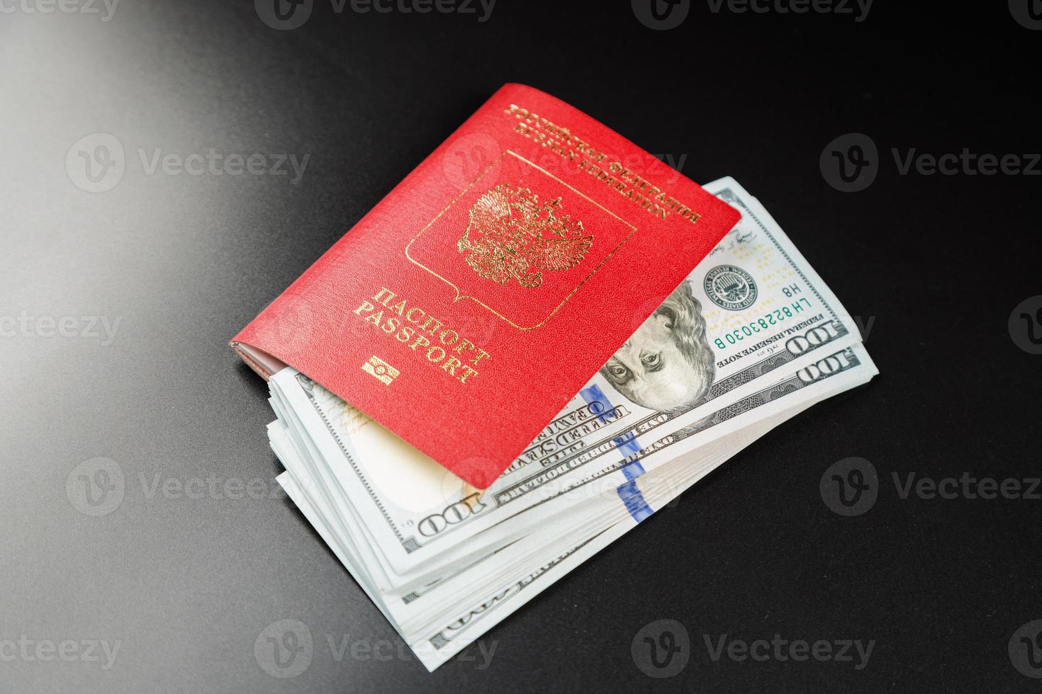 russian international passport with inserted US dollars on black background photo