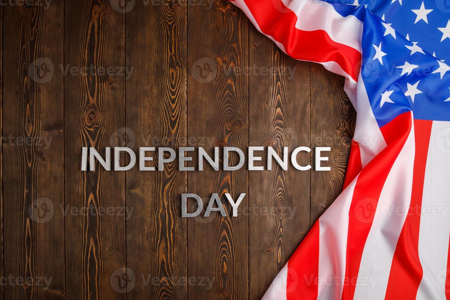 las palabras día de la independencia colocadas en la superficie de tablones de madera marrón con la bandera de los estados unidos de américa arrugada foto