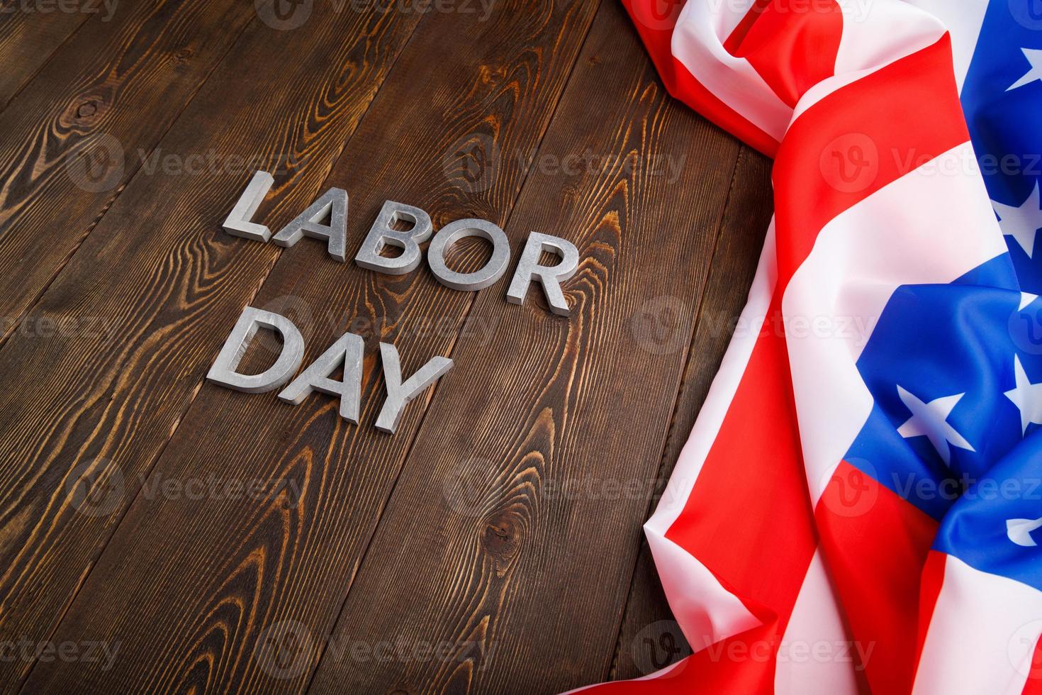 words labor day laid with silver metal letters on wooden surface with crumpled USA flag on left side photo