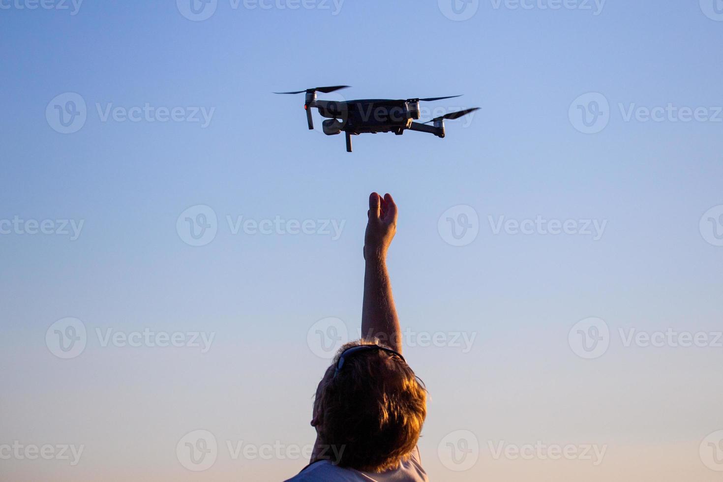 blonde caucasian man catching small quadcopter drone photo