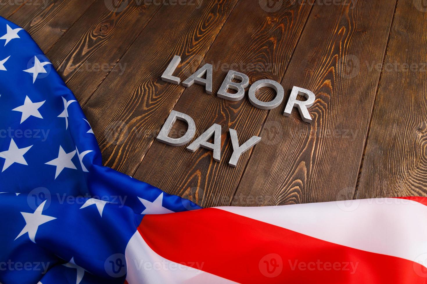 words labor day laid with silver metal letters on wooden surface with crumpled USA flag on bottom side photo