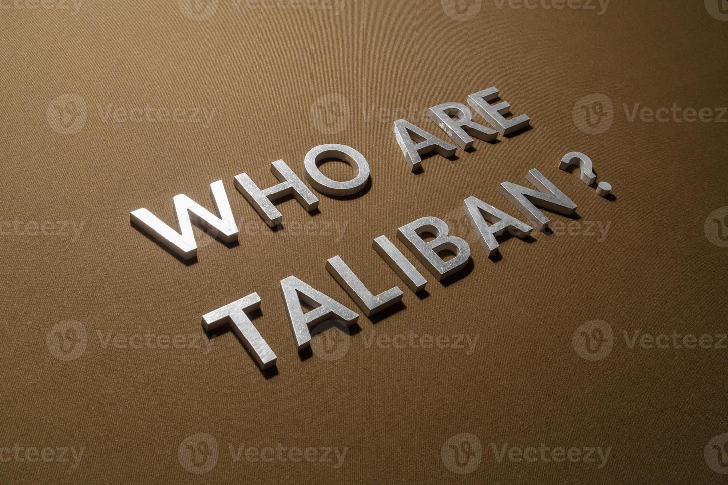 the question who are taliban laid with silver metal letters on rough tan khaki canvas fabric photo