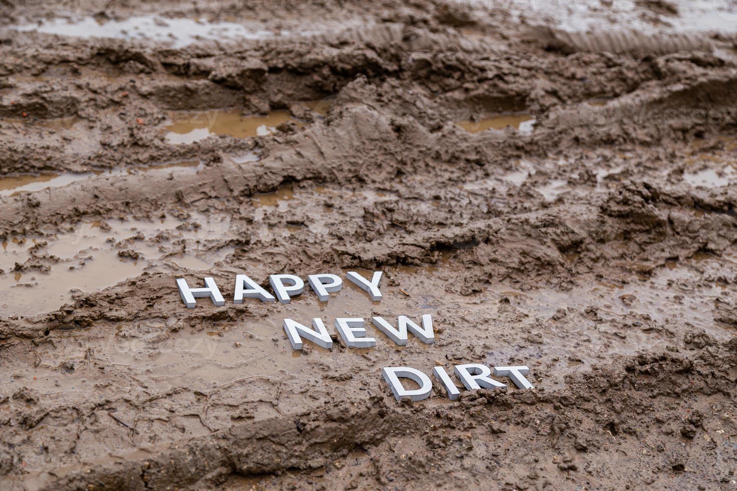 the words happy new dirt laid with silver metal letters on wet mud surface photo