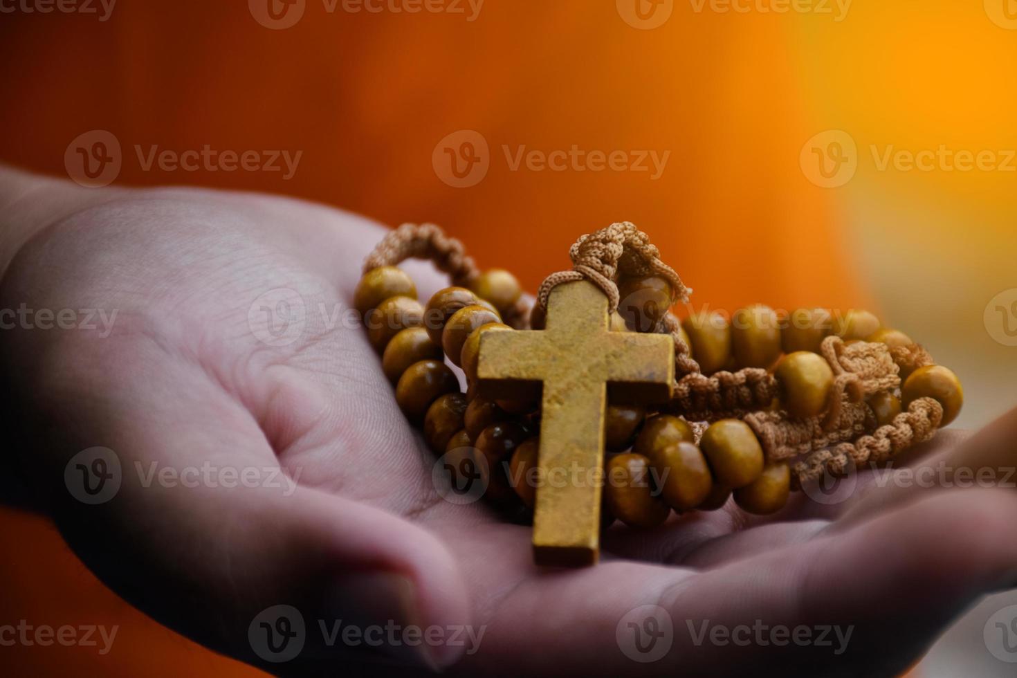 Closeup hands which offering wooden cross bead rosary to other people concept, soft and selective focus. photo