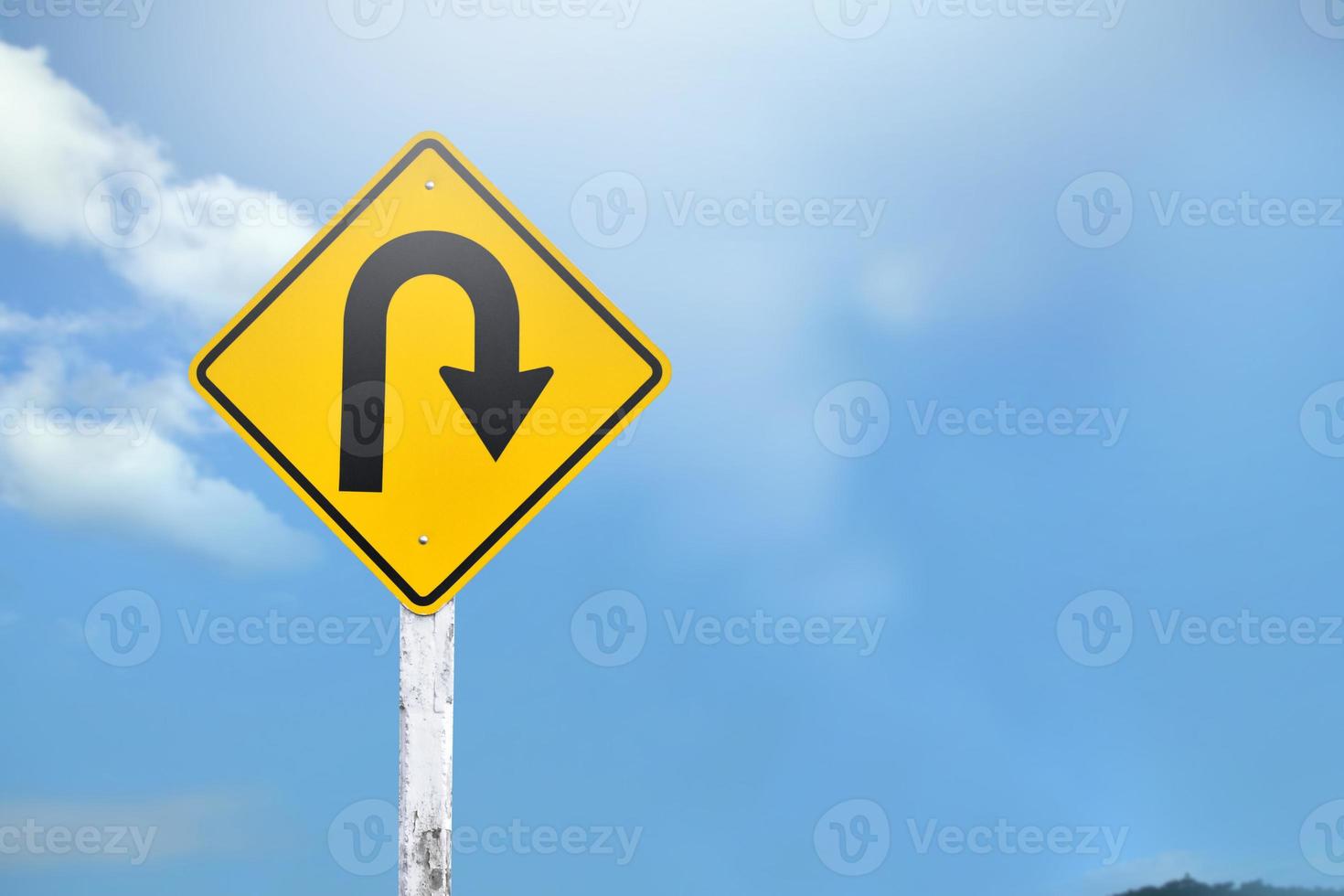 Traffic sign, Right U turn sign on cement pole beside the rural road with white cloudy bluesky background, copy space. photo