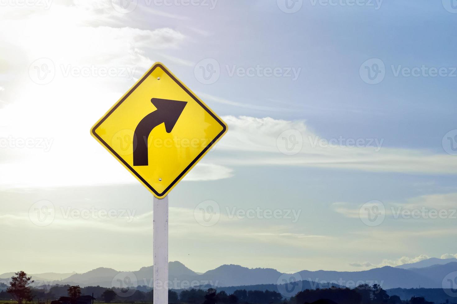 Traffic warning sign on pole, right curve means the way ahead is a right curve and should slow driving and drive carefully. photo