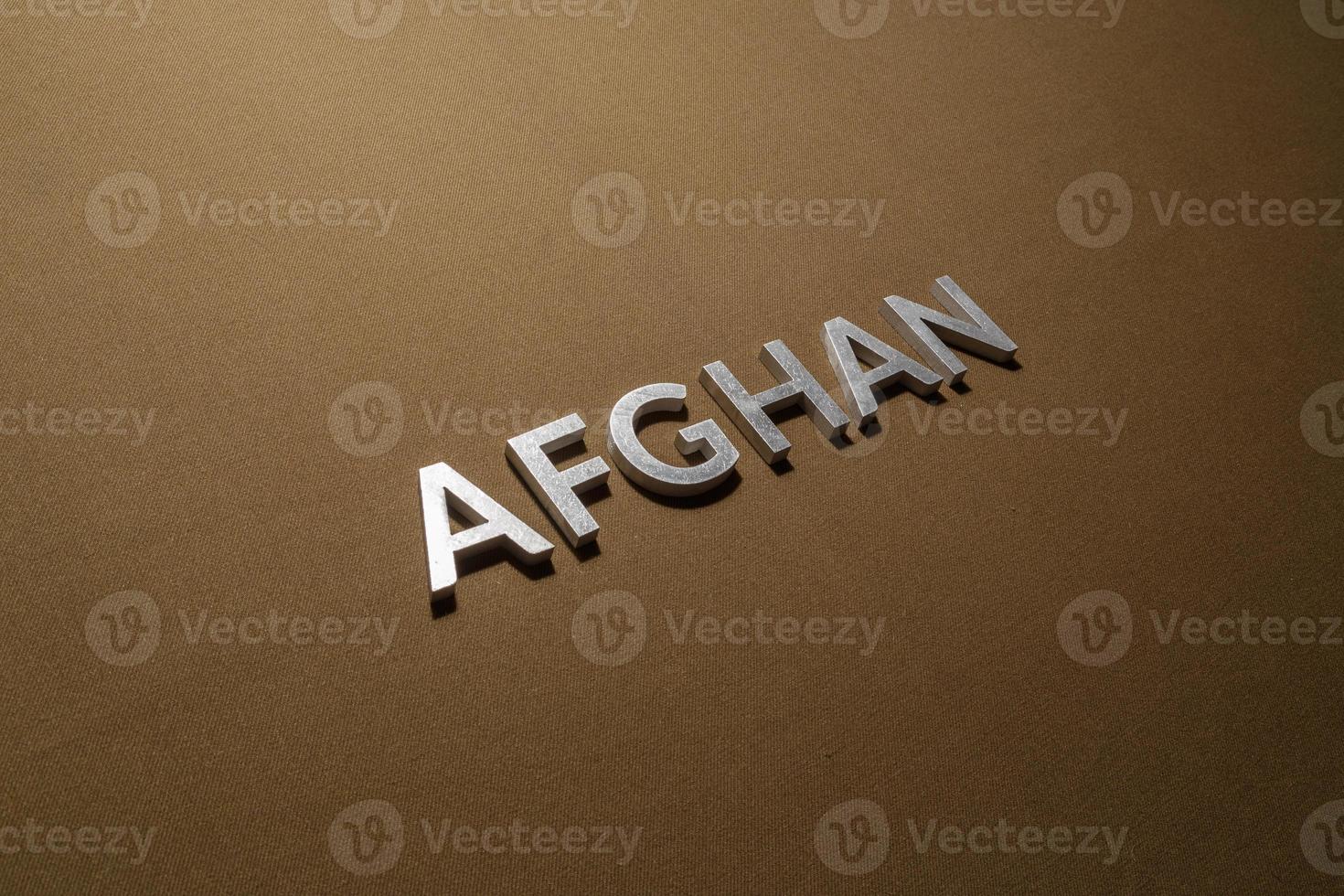 the word afghan laid with silver metal letters on rough tan khaki canvas fabric photo