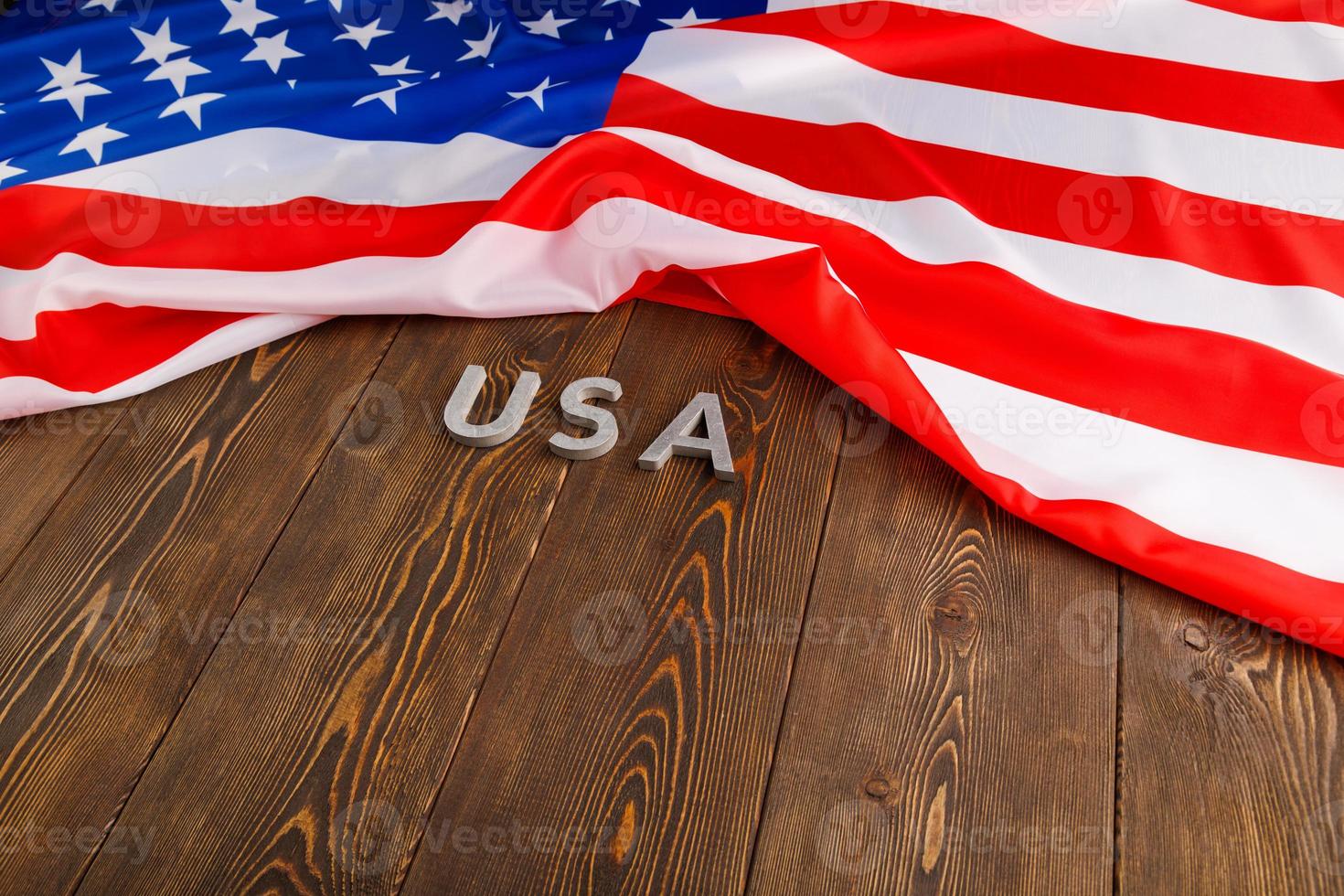 crumpled United States of America flag and with word USA laid with on flat textured wooden surface background photo