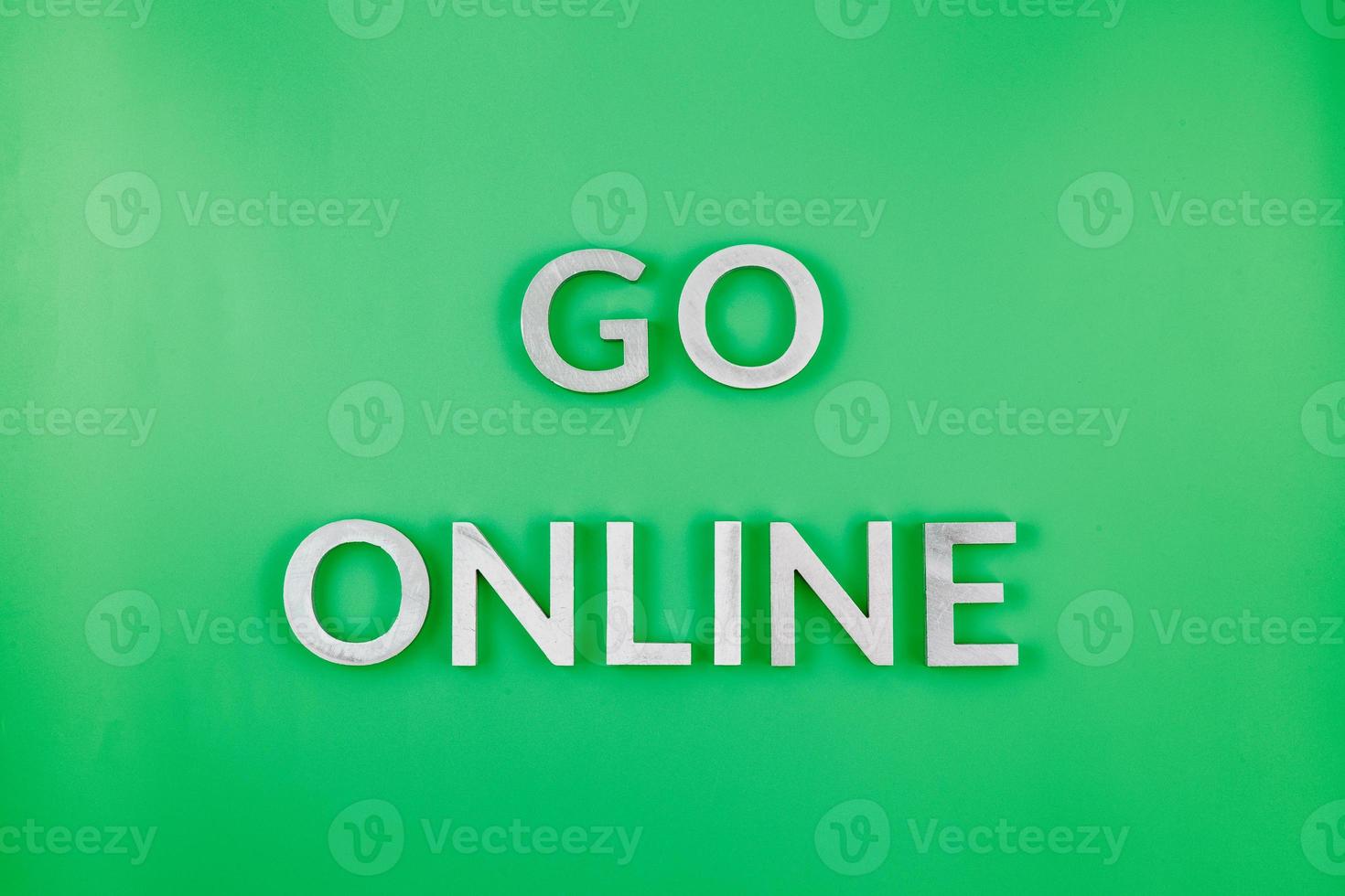 the words go online laid with brushed aluminium letters on green flat surface - close-up with flat lay composition photo