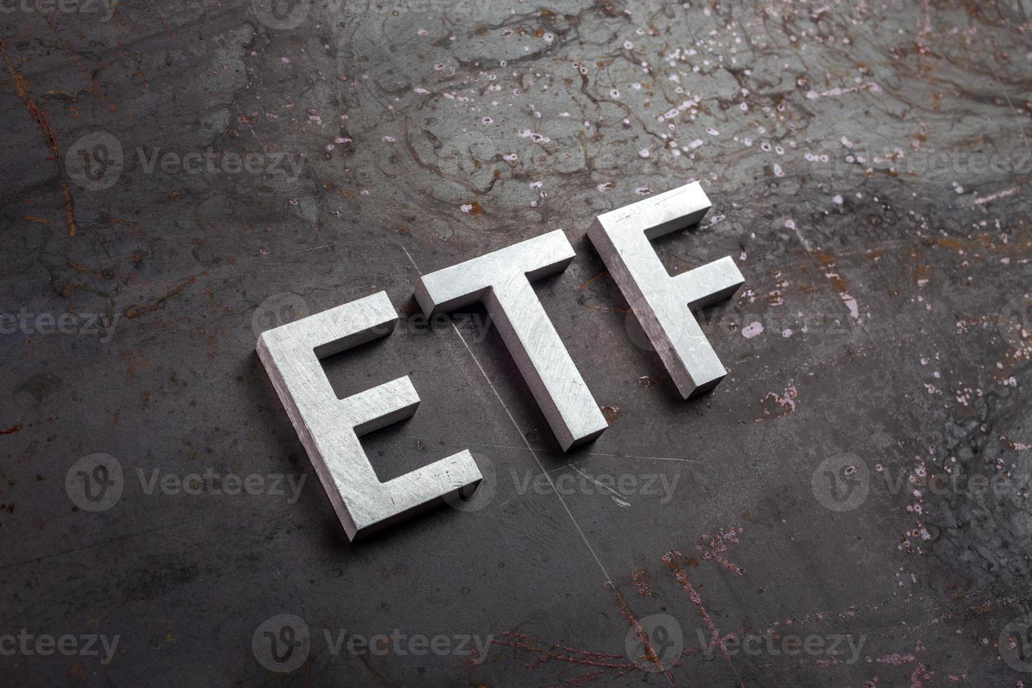 la palabra abreviada etf - fondo cotizado en bolsa - colocada con letras plateadas sobre una superficie de chapa de acero oxidada en perspectiva diagonal inclinada foto