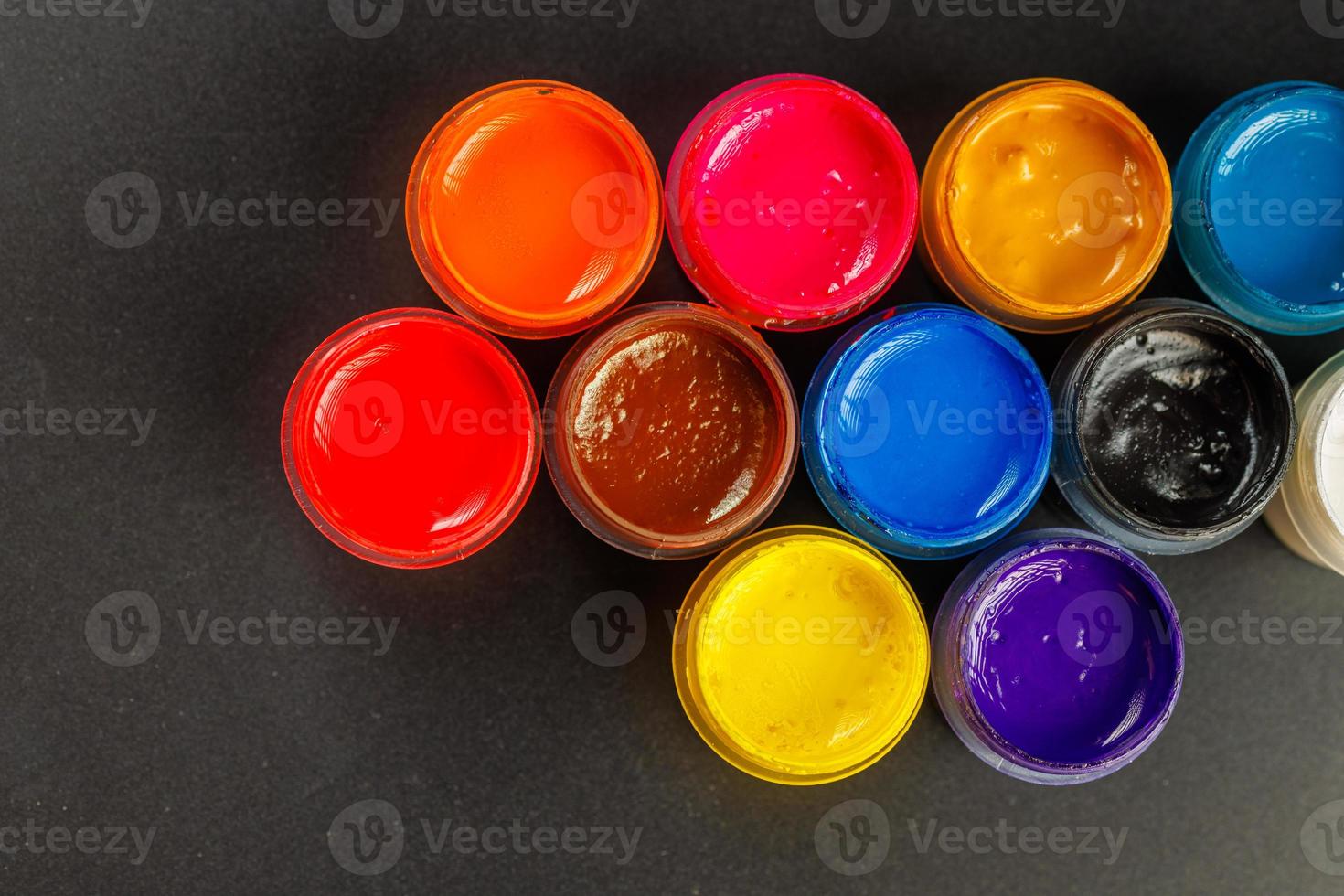 close-up background of opened small gouache paint jars on black surface photo
