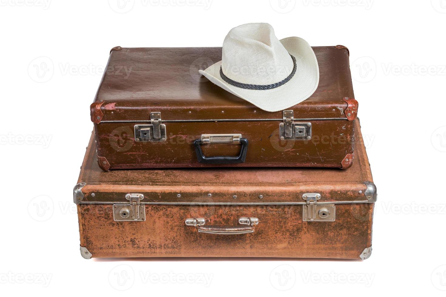 old soviet suitcases one on top of other with white summer hat isolated on white photo