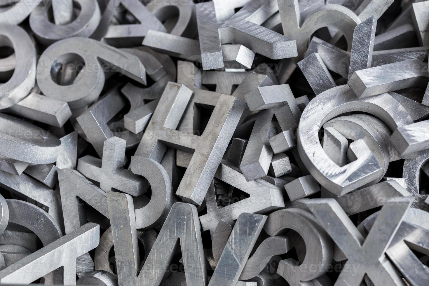 pile of silver metal alphabet characters cutted by waterjet machine photo