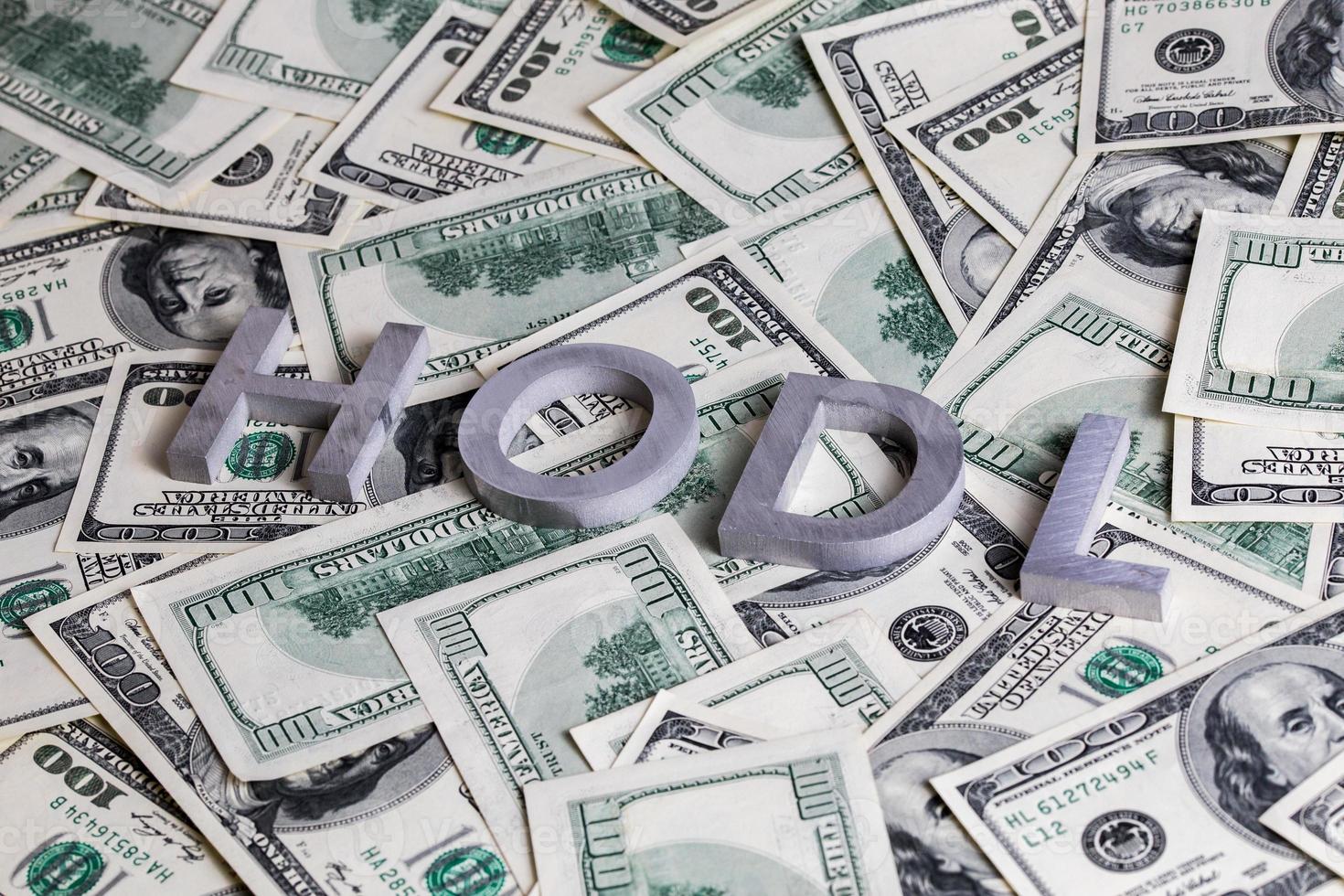 The words HODL laid with aluminium letters on dollar banknotes - with selective focus blur photo