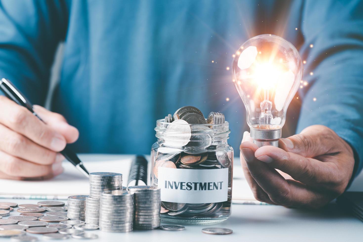 Young man holding a light bulb,coin in a glass jar,Finance and investment concepts, growth from profits and dividends,Investing in the stock market and trading cryptocurrencies,future income planning photo