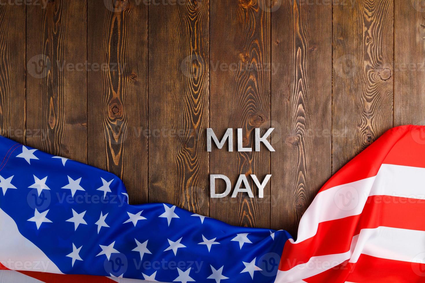 the word MLK day laid with silver metal letters on wooden surface with crumpled USA flag at lower side photo