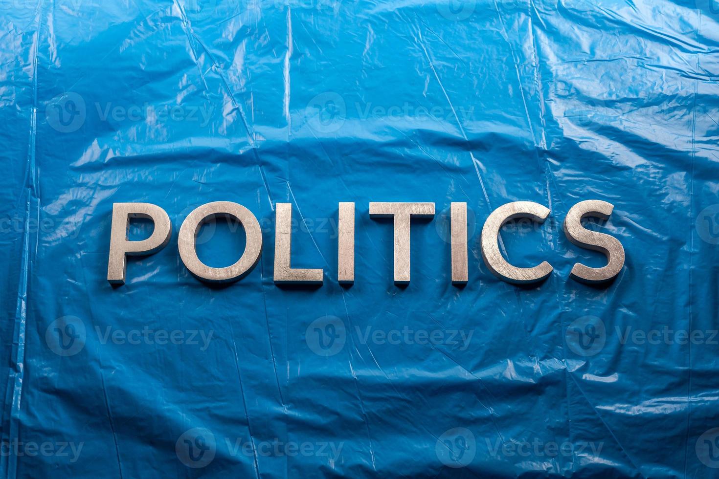 the word politics laid with silver aluminium letters over crumpled plastic blue film background - in center of picture photo