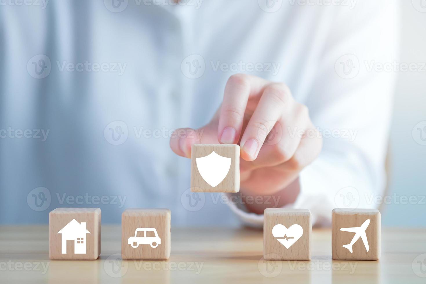 concepto de seguro. protección ante una posible eventualidad. mano que sostiene el ícono de seguridad y la casa, el automóvil, la atención médica y el ícono de viaje en un círculo de madera para garantizar el concepto de vida. foto