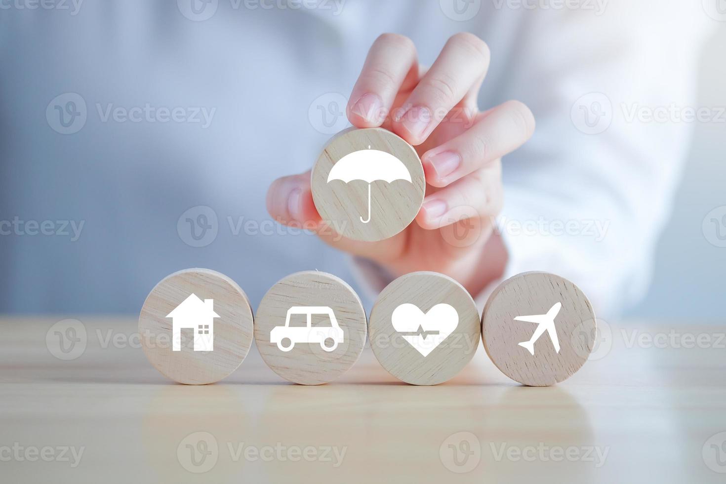 Insurance concept. Protection against a possible eventuality. Hand holding umbrella icon for security symbol and House, Car, Health care and travel icon on wooden circle for assurance life concept. photo