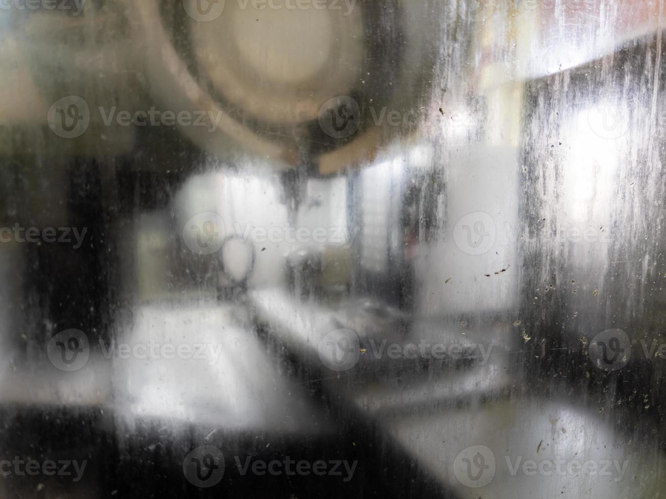 wet and dirty glass of cnc milling machine - close-up with selective focus and blur photo