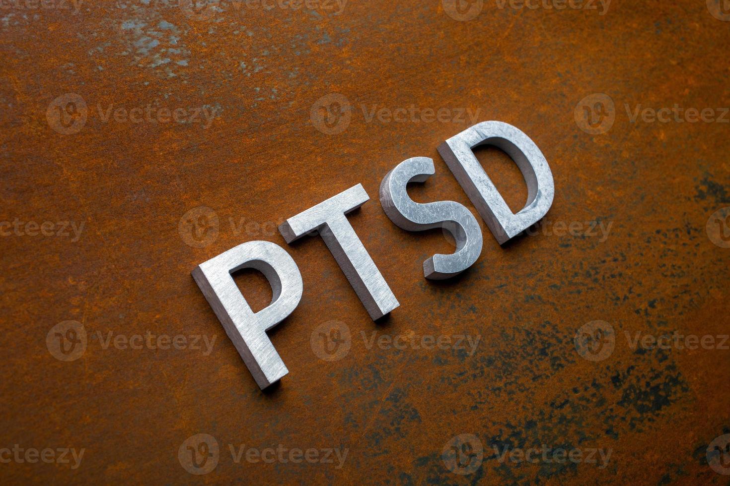 the word PTSD laid with silver metal letters on flat rusted steel sheet background in slanted diagonal perspective photo