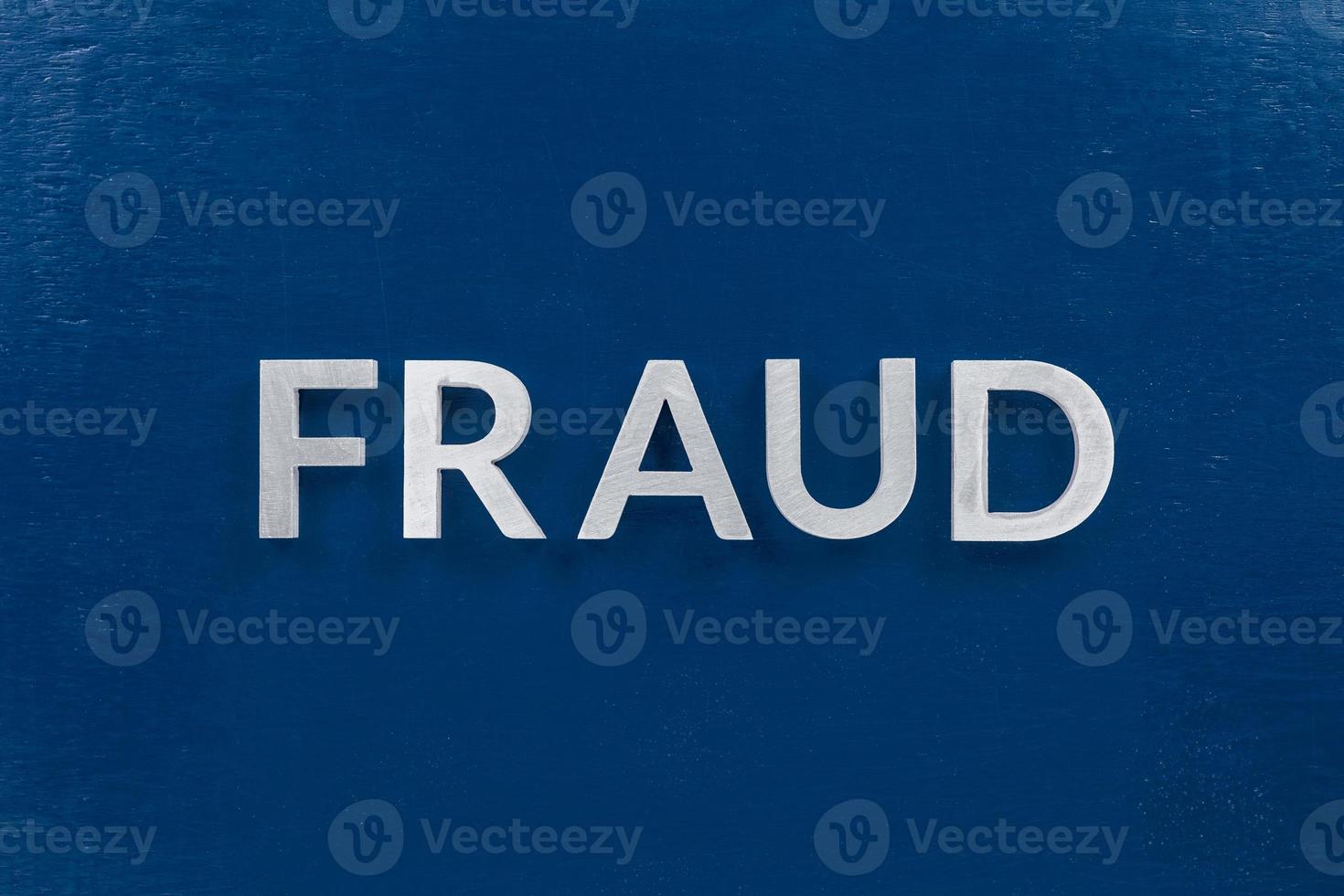 la palabra fraude colocada con letras de metal plateado en la clásica superficie de tablero pintada de azul foto