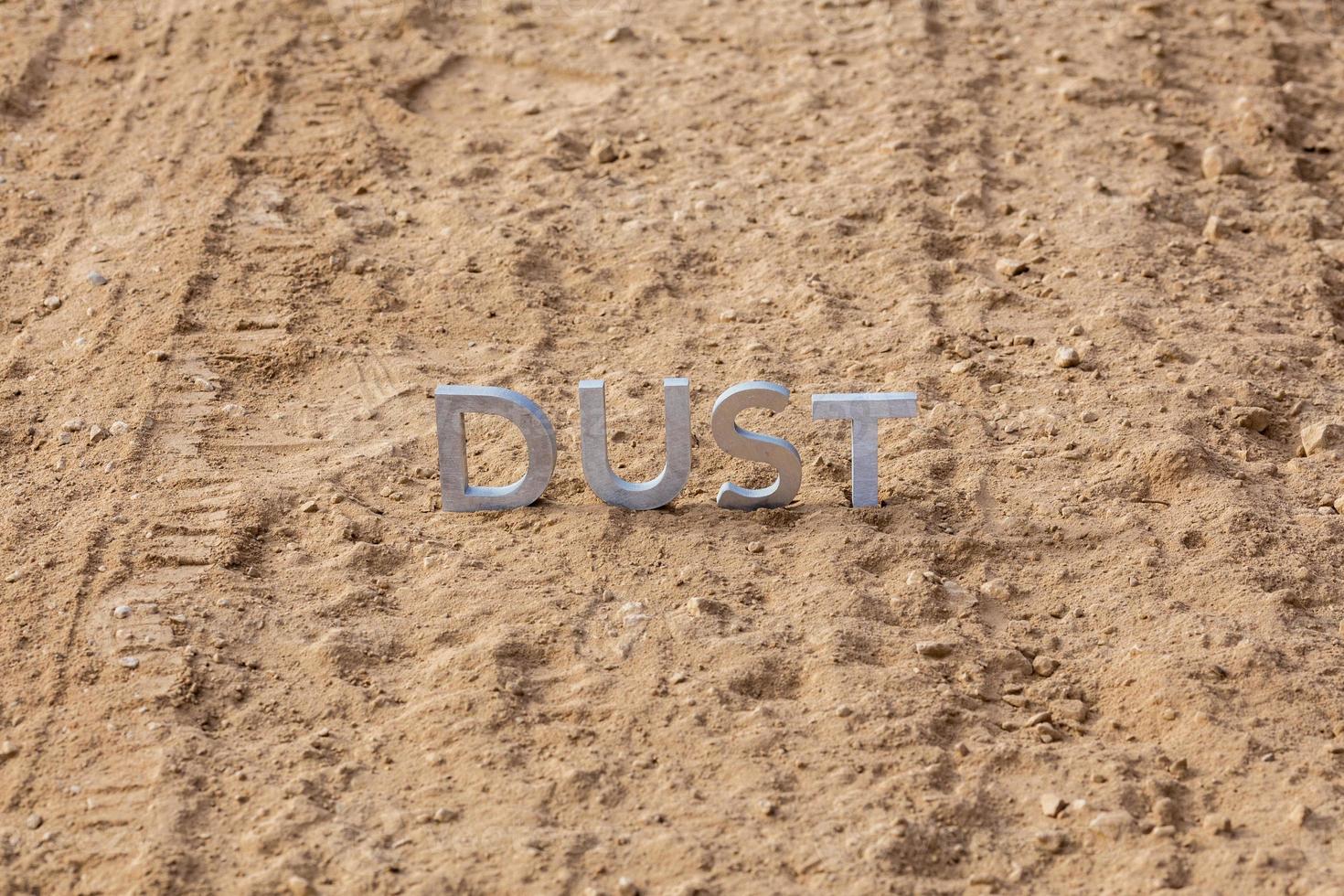 the word dust standing on dusty road surface in linear perspective photo