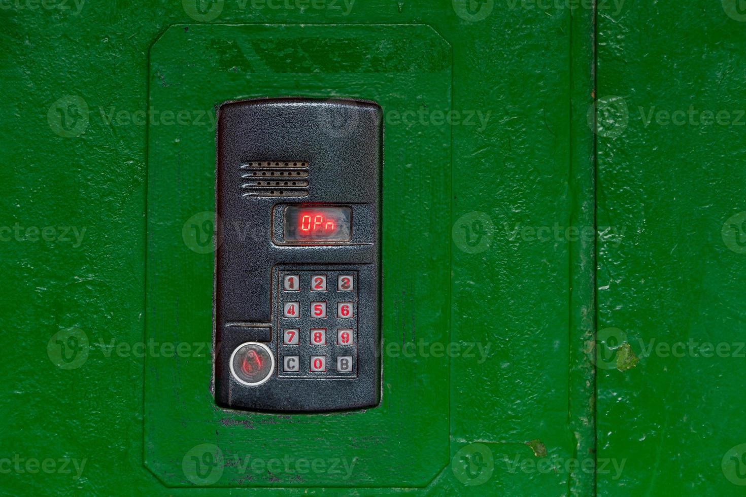 An intercom on green painted red steel surface with a keypad, digital display and rfid sensor for calling close-up photo