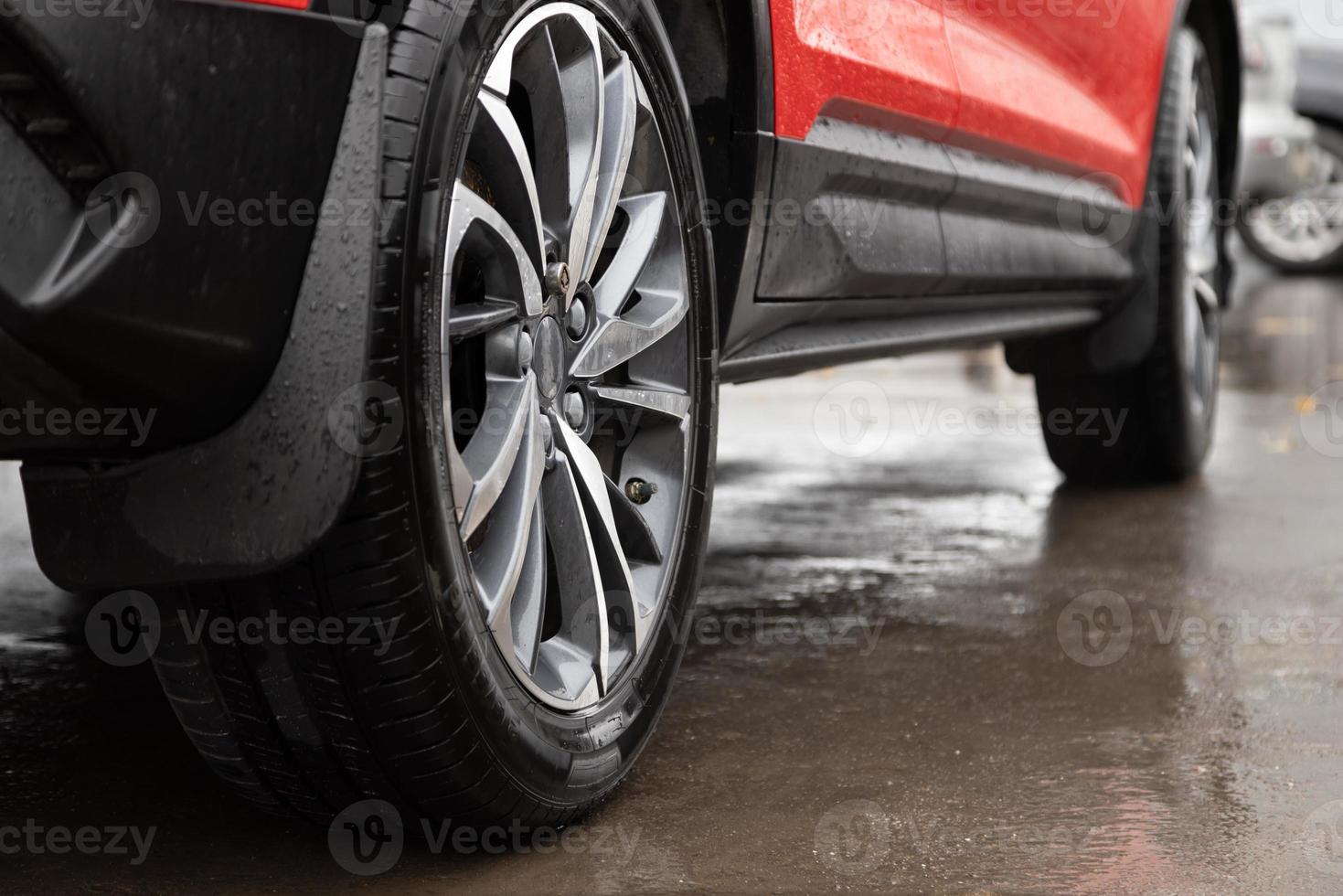 red car with secret bolt in wheel at rainy day, close-up with selective focus photo