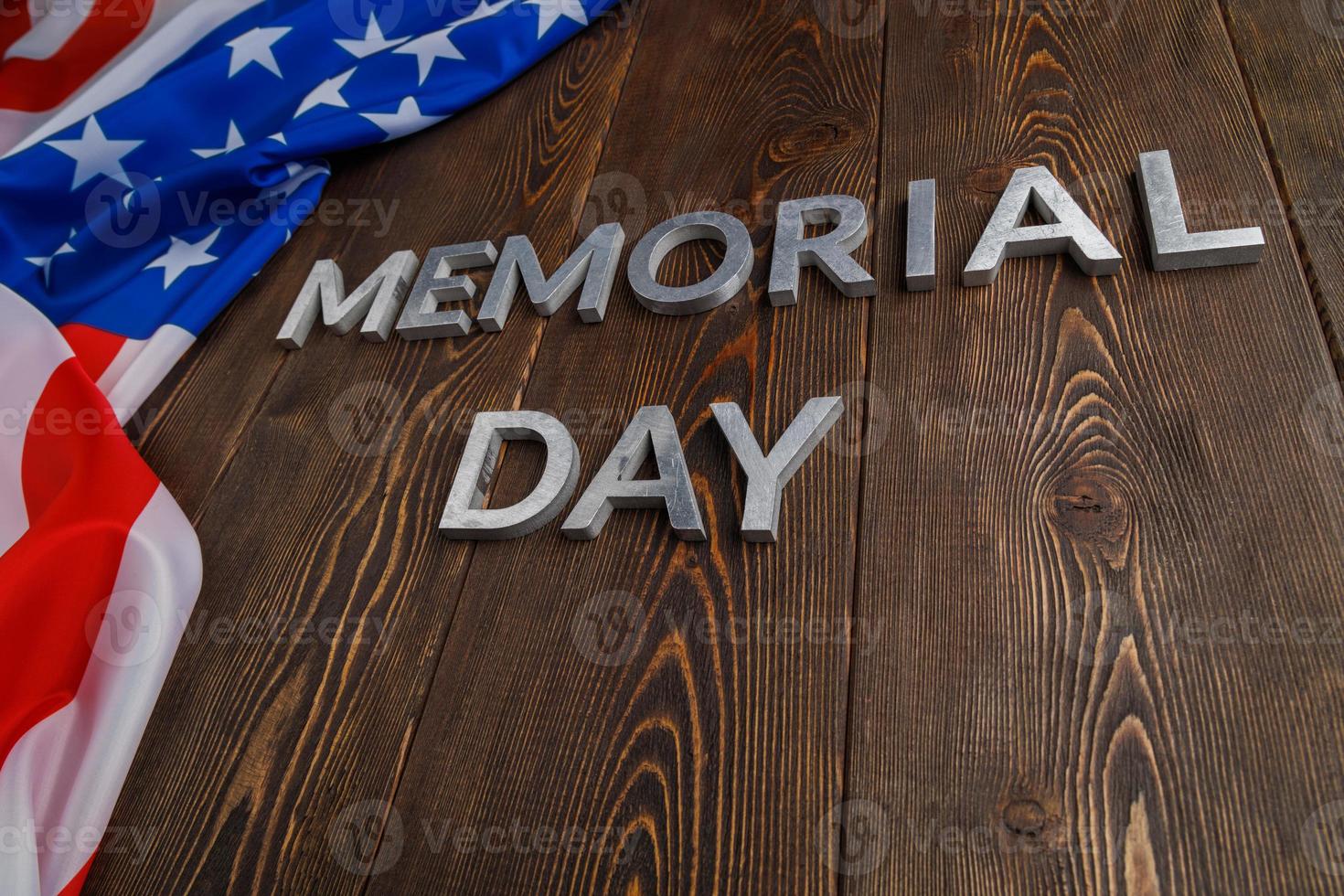 the words memorial day laid with silver metal letters on wooden board surface with crumpled usa flag photo