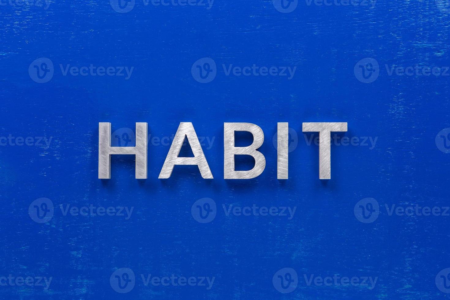 the word habit laid with silver metal characters on blue painted wooden board in central flat lay composition photo