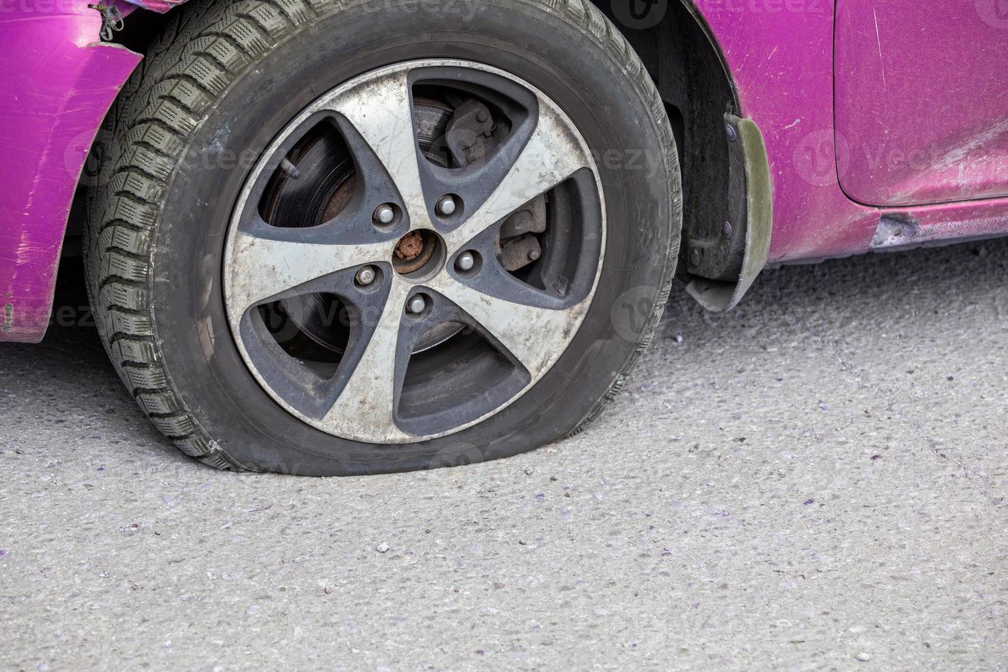 civil car flat tire close-up at dry sunny day on gray asphalt surface photo