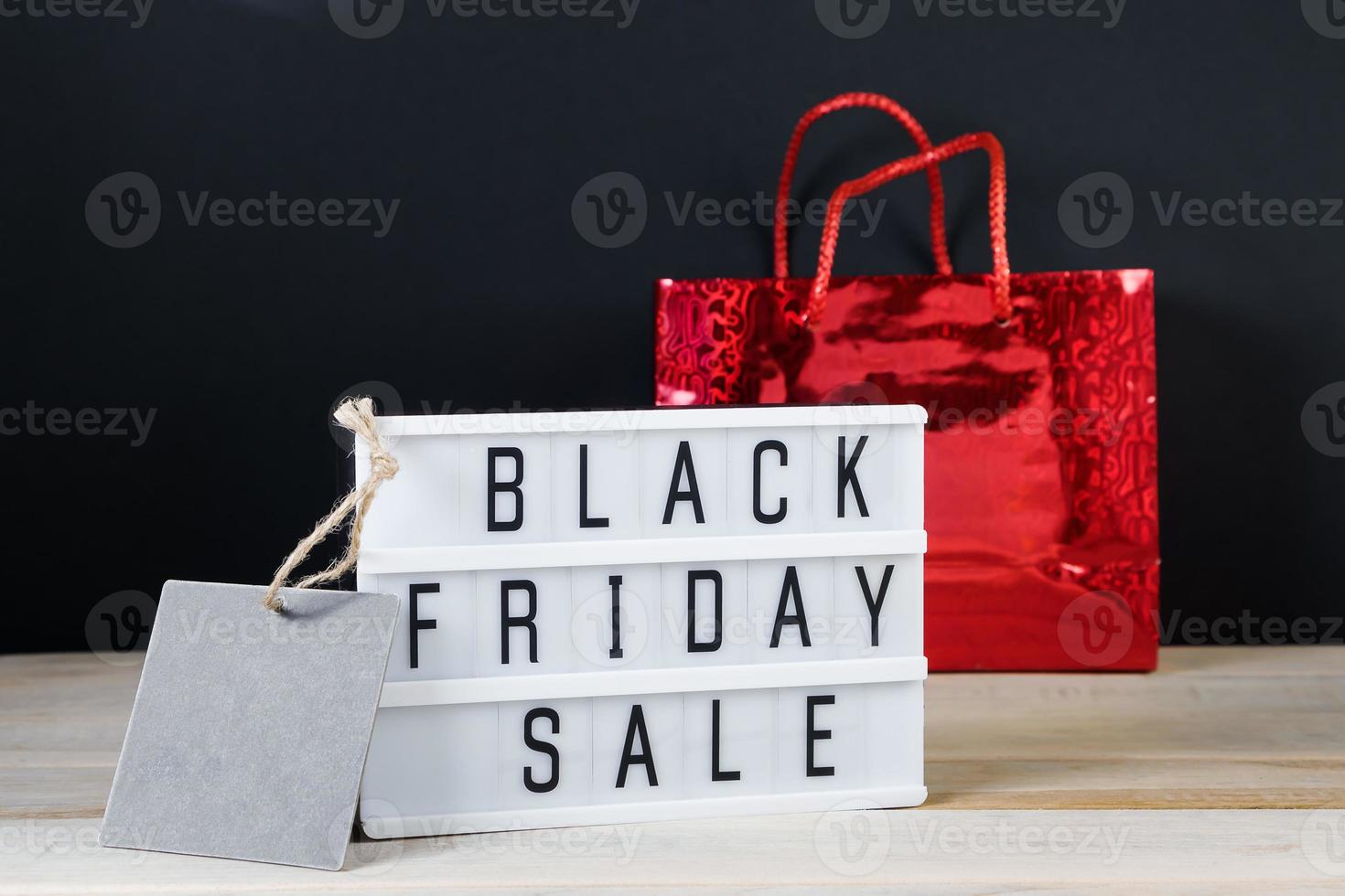 Black Friday sale concept. Label and red shopping bag on dark background. photo