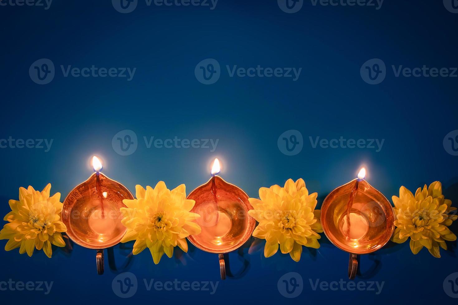 Happy Diwali. Diya oil lamps and yellow flowers on blue background. Celebrating the traditional Indian holiday of light. photo