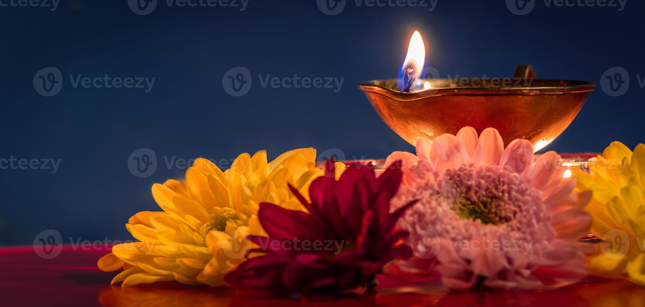 Happy Diwali. Traditional Indian festival of light. Burning diya oil lamps and flowers on red background. photo