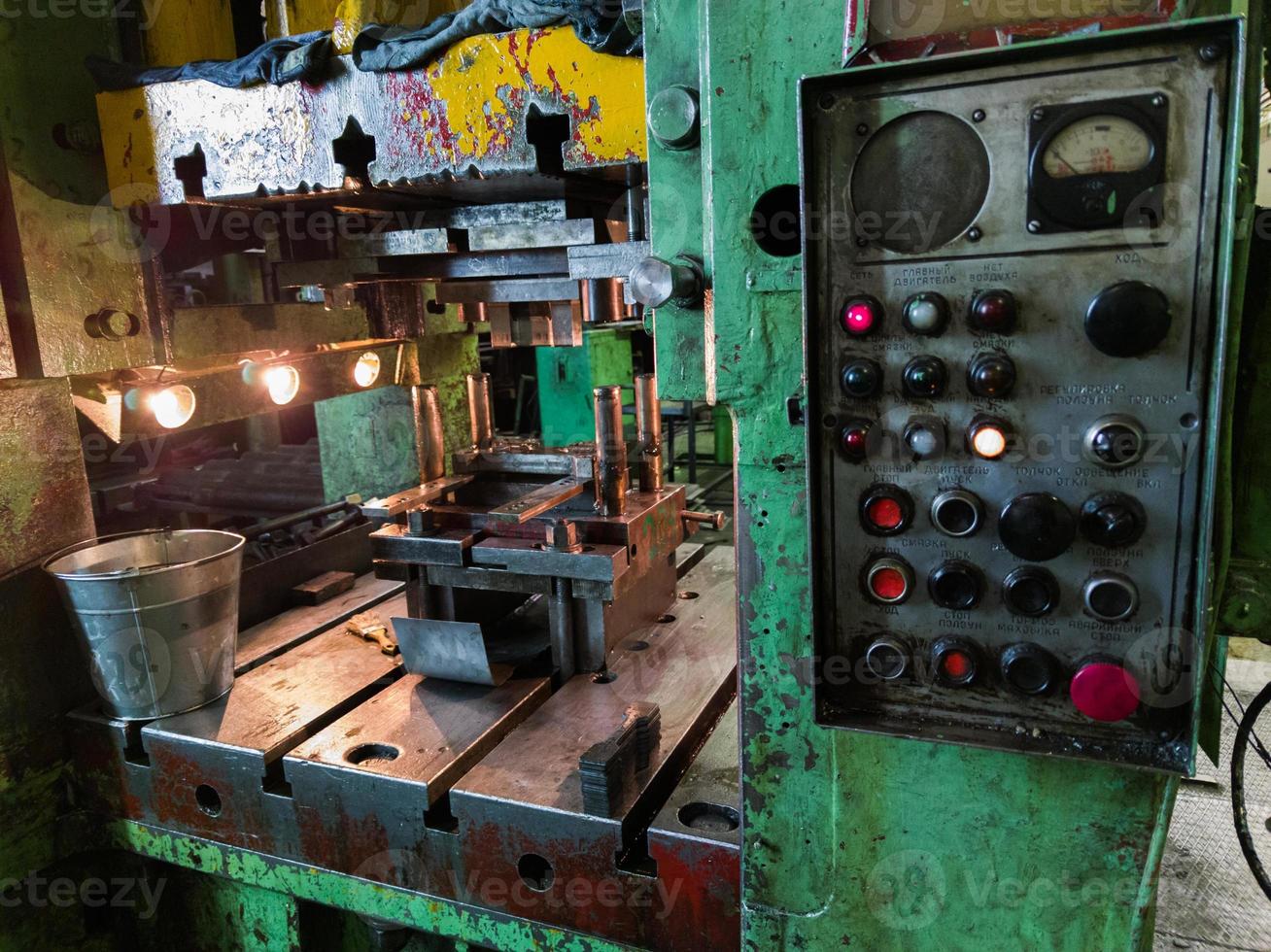 dirty used low tech stamping press in dark environment with large russian control panel photo