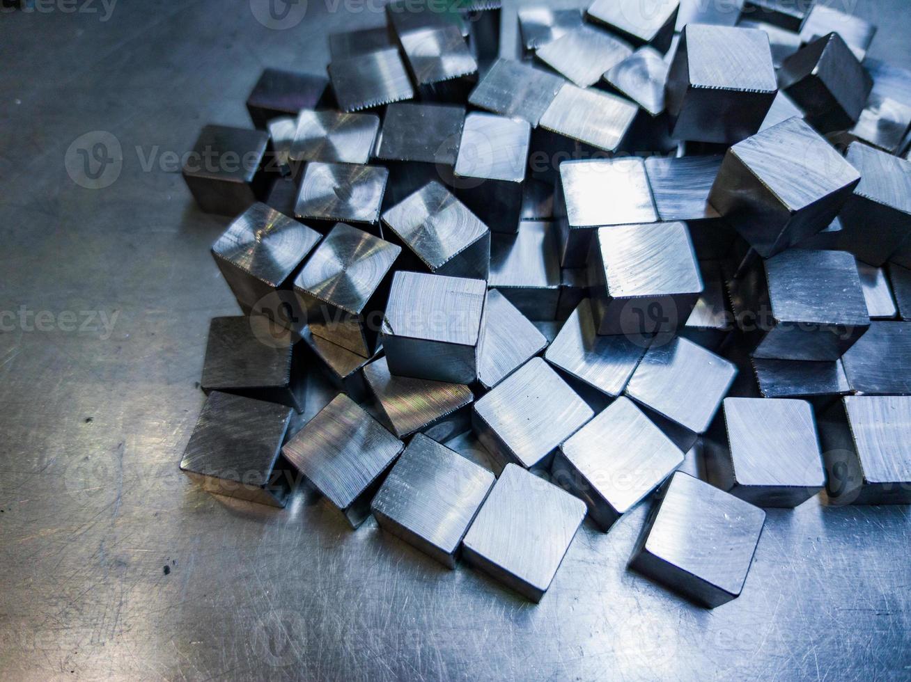 pile of small machined shiny steel cubes on metal surface photo