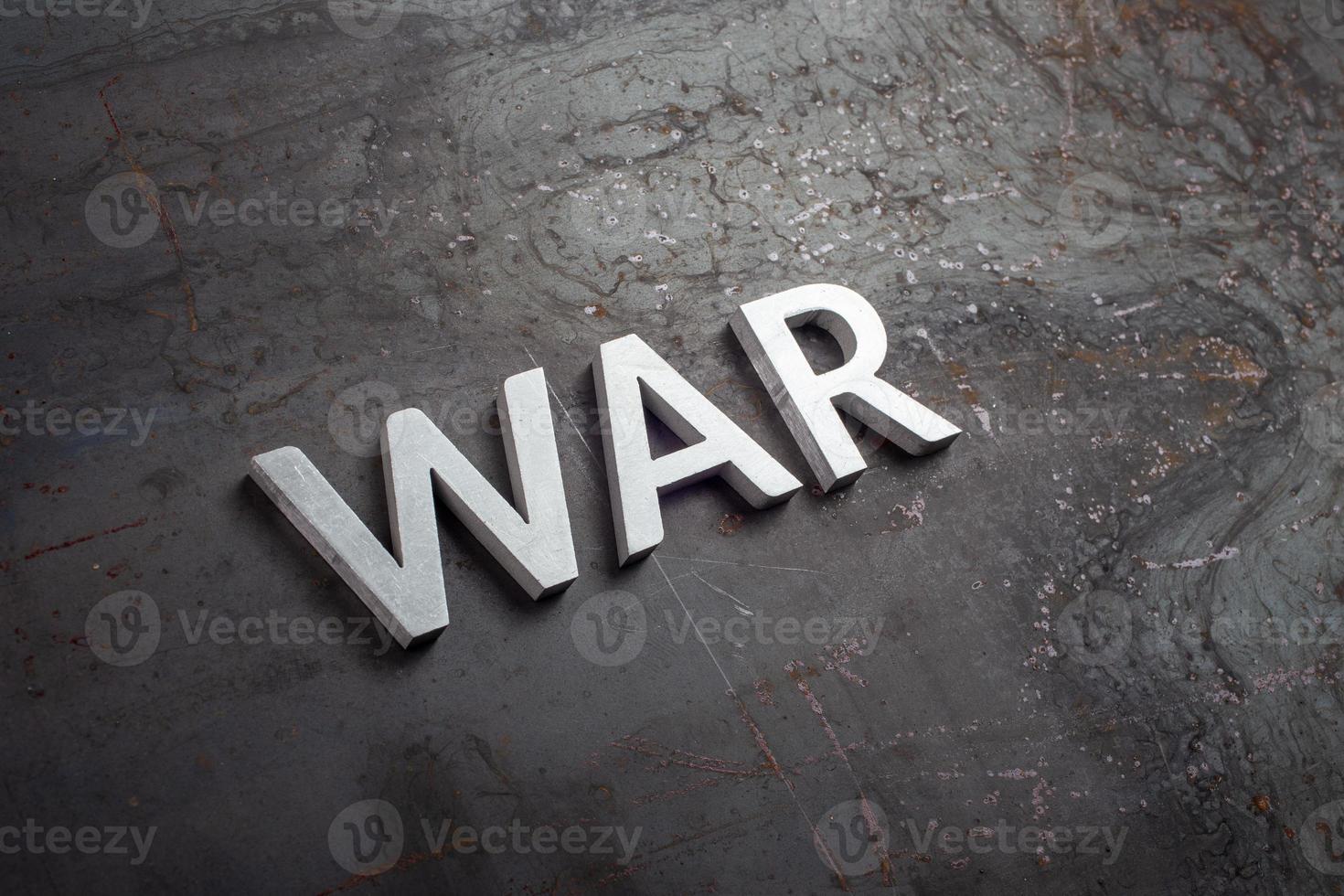 the word war laid with silver metal letters on black bare raw steel surface in slatted diagonal perspective photo