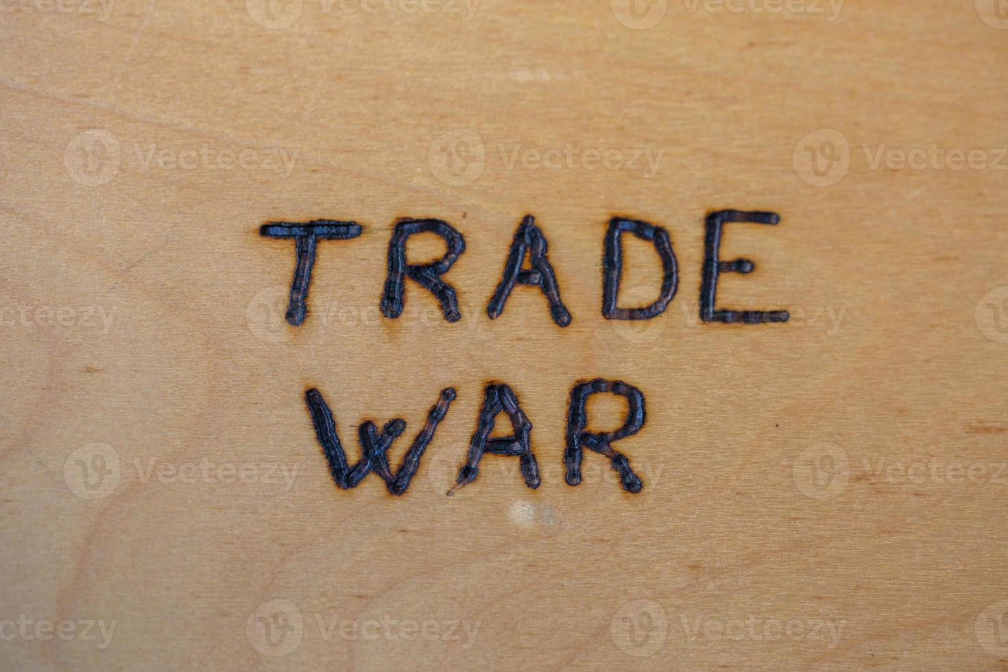 the words trade war handwritten on flat bare plywood surface with woodburner photo