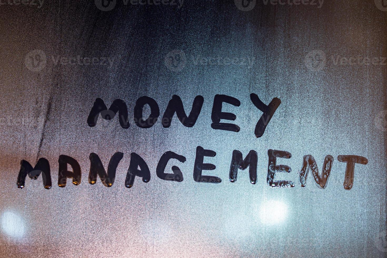 the words money management handwritten on night wet window glass with selective focus and blur in background photo