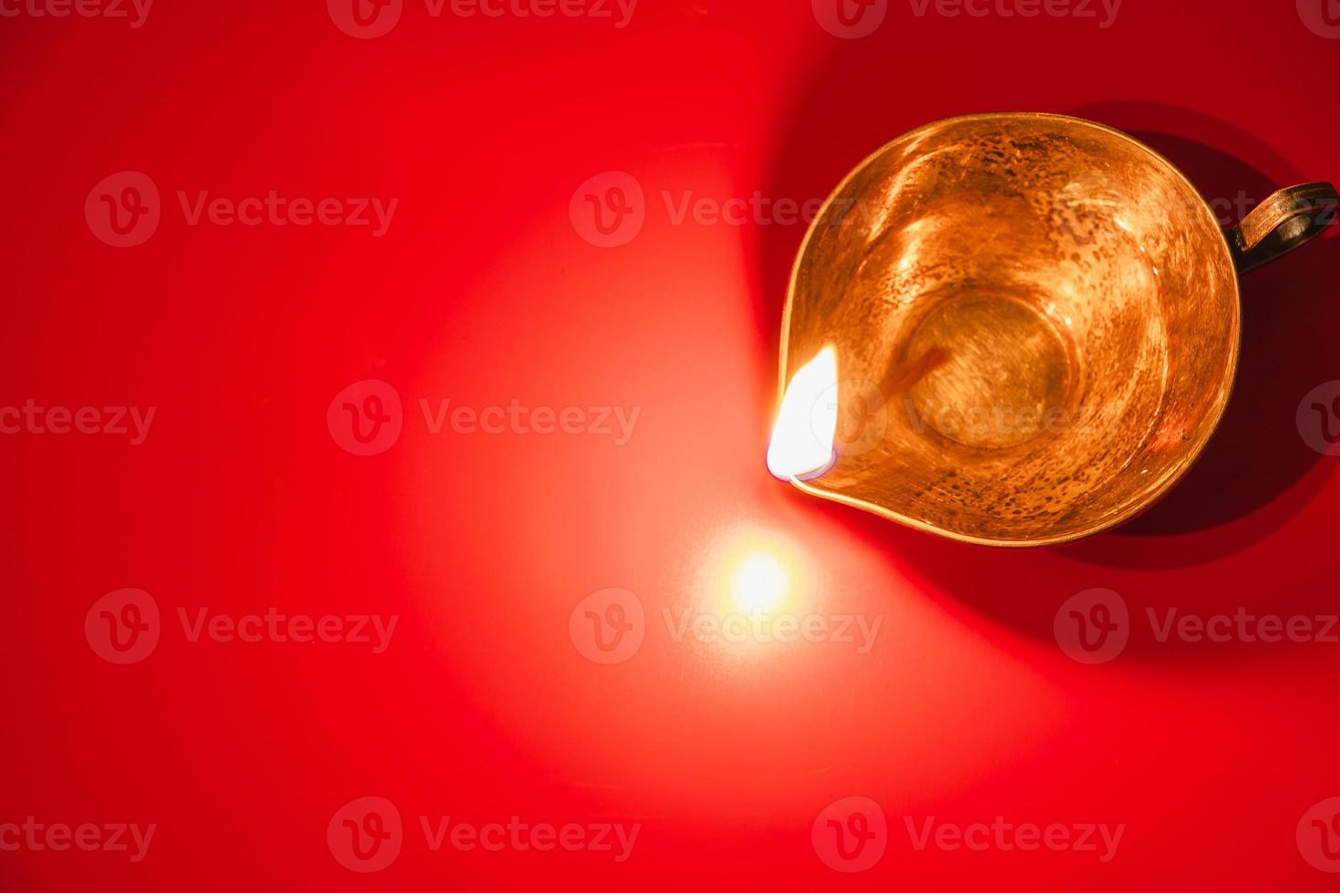 Burning diya oil lamp on red background. Celebrating the Indian traditional festival of light. Happy Diwali. photo