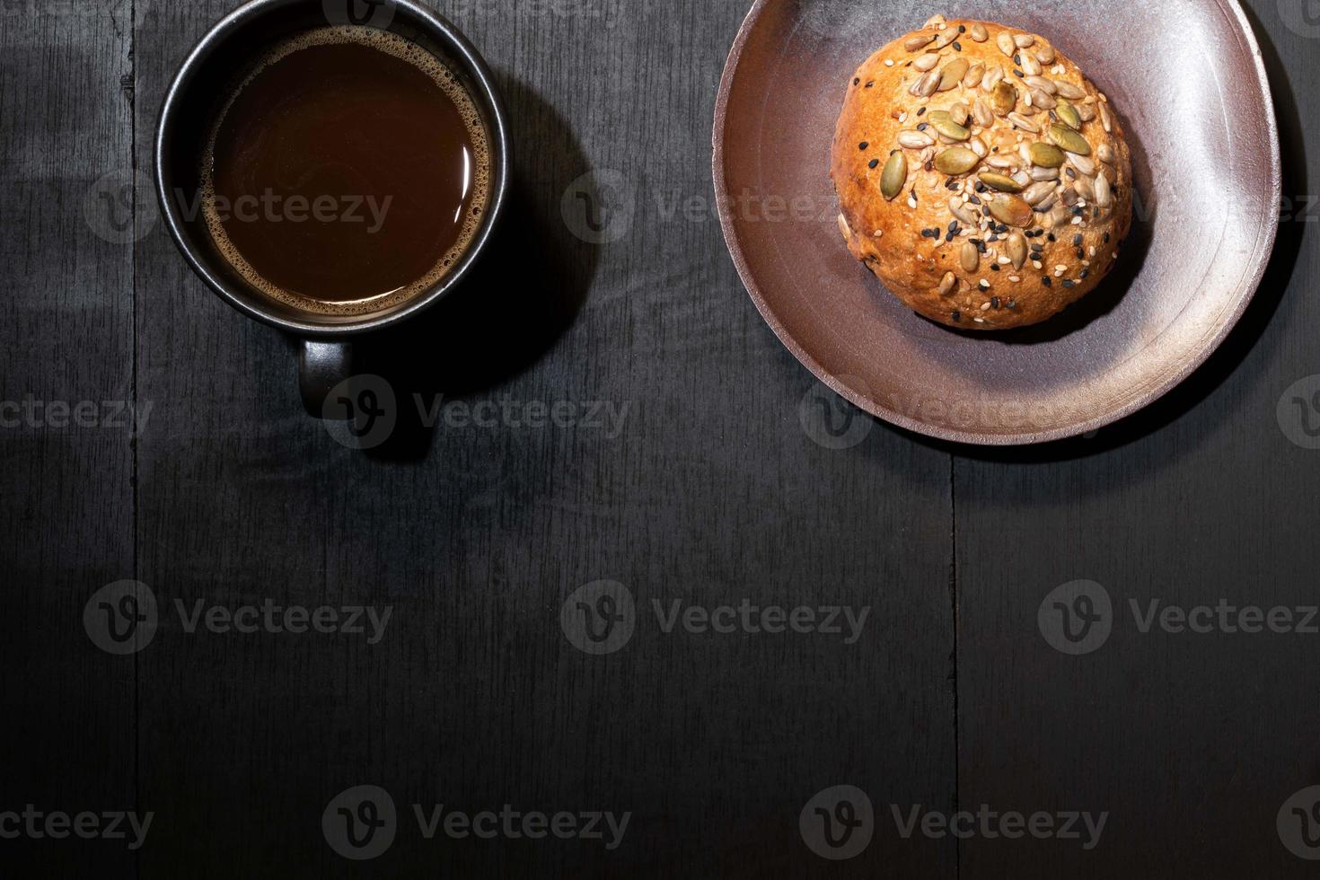 desayuno comida café y pan integral en plato sobre mesa de madera negra. foto