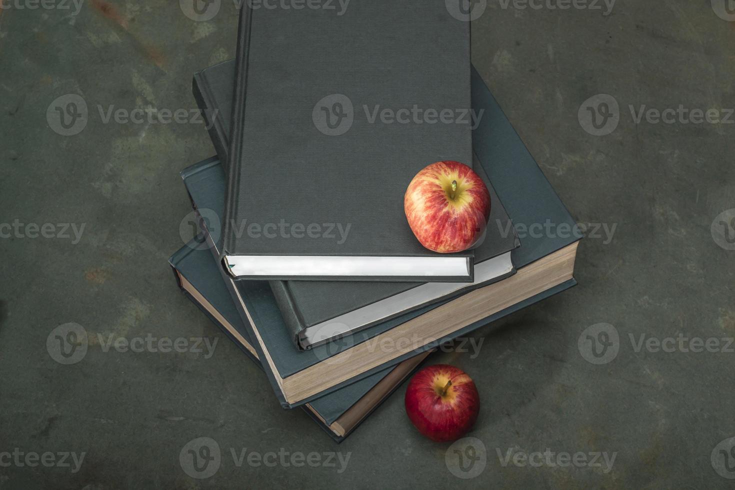 Apple on stack of book on green wood table study. photo