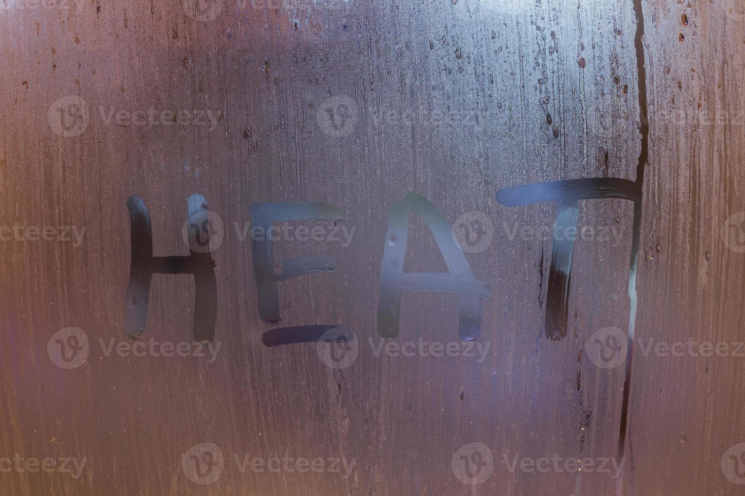 the word heat written on night wet window glass close-up with bokeh background photo