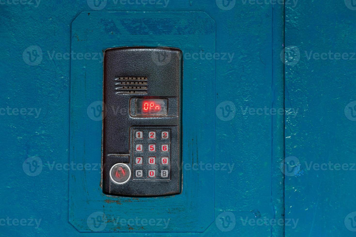 An intercom on old painted blue steel surface with a keypad, digital display and rfid sensor for calling close-up photo